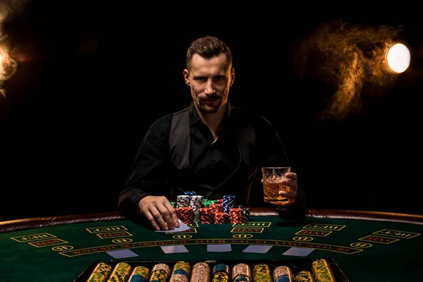 Joueur de poker. Jeune homme dans le casino à la table de jeu. Le jeu d'homme, les jeux de cartes. Cartes, jetons, whisky, cigarettes, poker, jeu de cartes, jeu - concept de jeu . — Photo