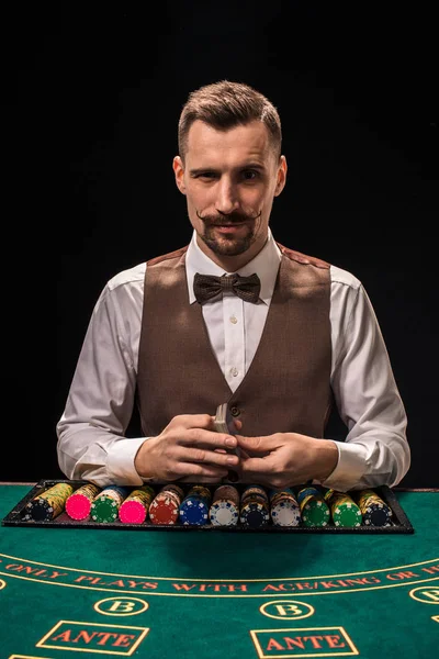 Das Porträt eines Croupier hält Spielkarten und Spielchips auf dem Tisch. schwarzer Hintergrund — Stockfoto