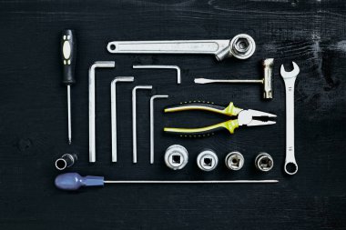 Siyah ahşap arka plan üzerine pense soket anahtarı ve tornavida araçlar kümesi anahtarı