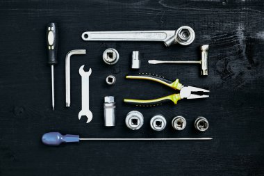 Siyah ahşap arka plan üzerine pense soket anahtarı ve tornavida araçlar kümesi anahtarı