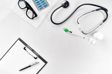 Stetoskop doktor ofisinde. Üstten Görünüm doktorlar Resepsiyon tablo, boş kağıt kalem ile Pano üzerinde. Uzay kopyalayın. Tasarımcılar boş