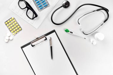 Stetoskop doktor ofisinde. Üstten Görünüm doktorlar Resepsiyon tablo, boş kağıt kalem ile Pano üzerinde. Uzay kopyalayın. Tasarımcılar boş