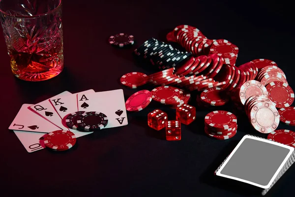 Cards of poker player. On the table are chips and a glass of cocktail with whiskey. Combination of cards - Royal Flush