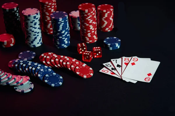 Casino chips and cards on black table surface. Gambling, fortune, game and entertainment concept - close up — Stock Photo, Image