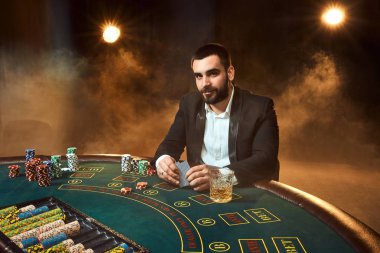 Poker masasında oturan iş elbiseli bir genç adam. Adam gambles. Oyun Masa oyun kağıtları, oyuncu.