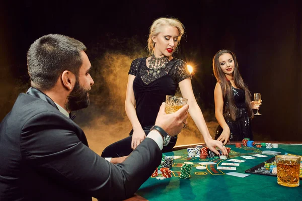 Group of young rich people is playing poker in the casino