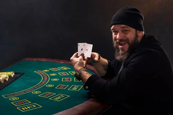 Бородатий чоловік показує покерні карти на чорному тлі — стокове фото