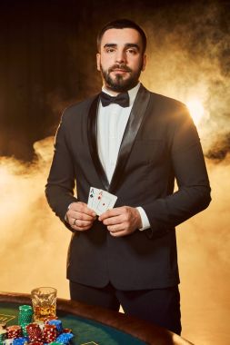 Poker masasında duran iş elbiseli bir genç adam. Adam sakınacak.