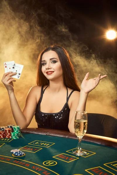 Gorgeous νεαρή γυναίκα που κάθεται στο τραπέζι πόκερ με ποτήρι σαμπάνια — Φωτογραφία Αρχείου