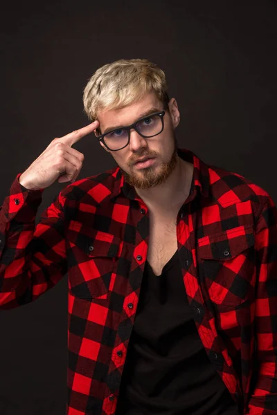 Knappe trendy jonge kerel in de studio op zwarte achtergrond. Hij draagt baard en een plaid shirt — Stockfoto