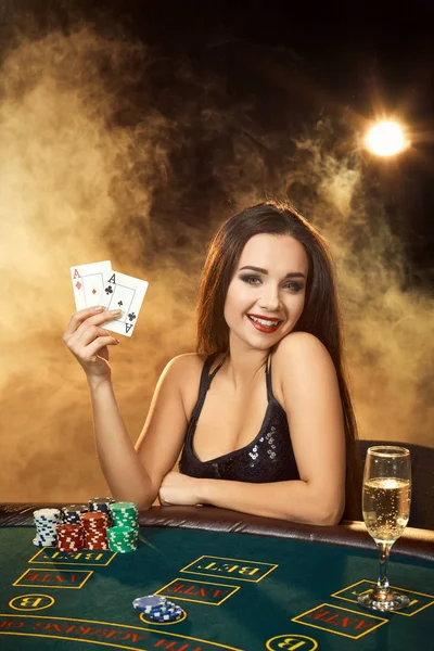 Nádherná mladá žena sedí u pokerového stolu se sklenkou šampaňského — Stock fotografie