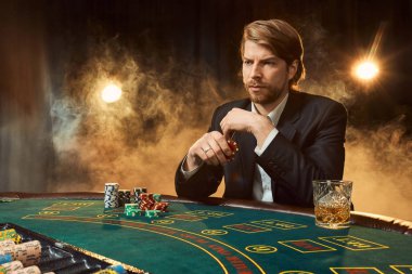 Oyun masada oturan iş elbiseli bir adam. Erkek oyuncu. Tutku, kartları, cips, alkol, kumar, casino - zar, o erkek eğlence 's.