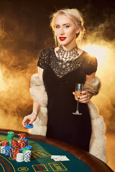 Porträtt av kvinna att hålla pokermarker nära bord i casino — Stockfoto
