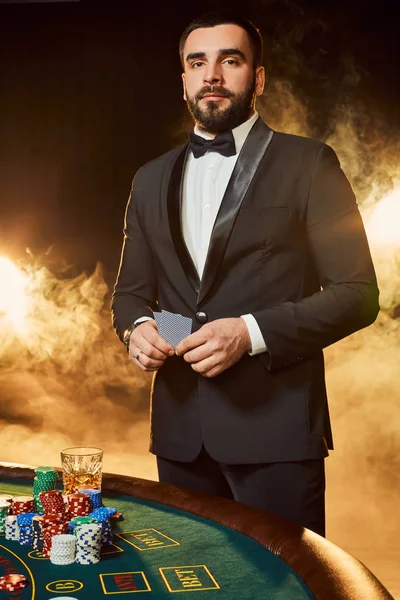 Un giovane uomo in giacca e cravatta vicino al tavolo da poker. Uomo gioca d'azzardo . — Foto Stock