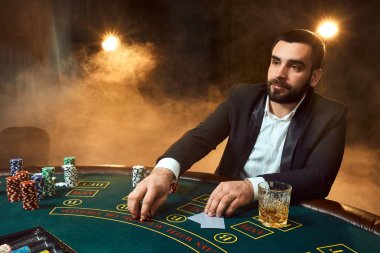 Poker masasında oturan iş elbiseli bir genç adam. Adam gambles. Oyun Masa oyun kağıtları, oyuncu.
