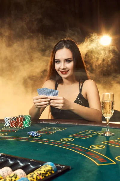 Ursnygg ung kvinna sitter vid pokerbordet med glas champagne — Stockfoto