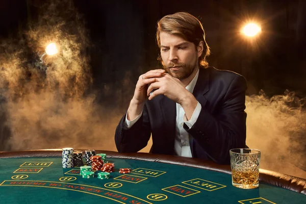 Oyun masada oturan iş elbiseli bir adam. Erkek oyuncu. Tutku, kartları, cips, alkol, kumar, casino - zar, o erkek eğlence 's.
