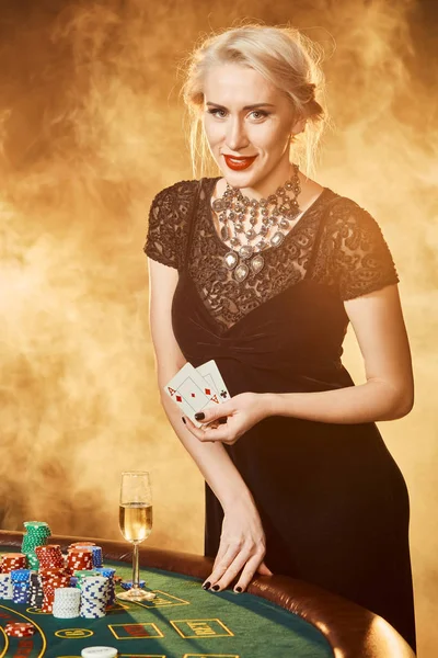 ポーカー テーブルの近く彼女の手の中のカードで黒ドレスを着た女性が立っています。 — ストック写真