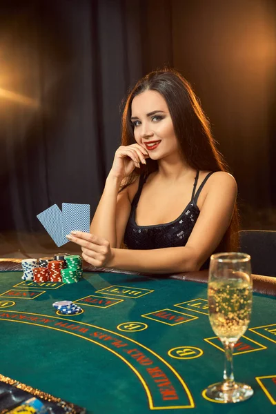 Hermosa joven sentada en la mesa de póquer con una copa de champán — Foto de Stock