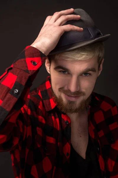 Guapo joven de moda en el estudio sobre fondo negro. Lleva barba y camisa a cuadros. —  Fotos de Stock