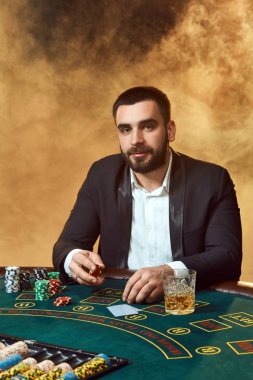 Poker masasında oturan iş elbiseli bir genç adam. Adam gambles. Oyun Masa oyun kağıtları, oyuncu.
