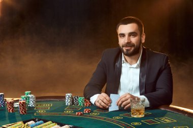 Poker masasında oturan iş elbiseli bir genç adam. Adam gambles. Oyun Masa oyun kağıtları, oyuncu.