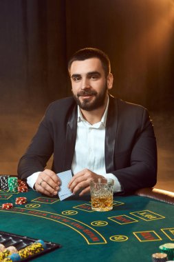 Poker masasında oturan iş elbiseli bir genç adam. Adam gambles. Oyun Masa oyun kağıtları, oyuncu.