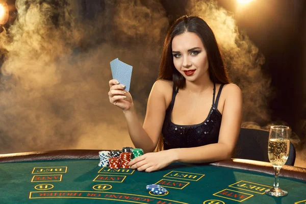 Hermosa joven sentada en la mesa de póquer con una copa de champán — Foto de Stock
