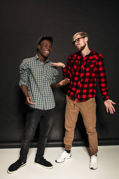 Studio lifestyle portrait of two best friends hipster boys going crazy and having great time together. On black background.