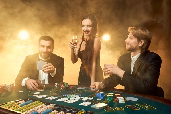 Group of young rich people is playing poker in the casino