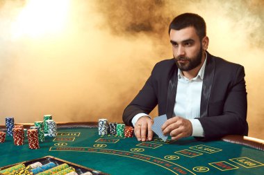 Poker masasında oturan iş elbiseli bir genç adam. Adam gambles. Oyun Masa oyun kağıtları, oyuncu.