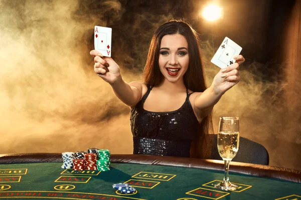 Hermosa joven sentada en la mesa de póquer con una copa de champán — Foto de Stock