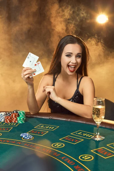 Hermosa joven sentada en la mesa de póquer con una copa de champán — Foto de Stock