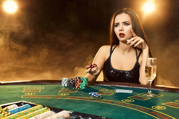 Nádherná mladá žena sedí u pokerového stolu se sklenkou šampaňského — Stock fotografie