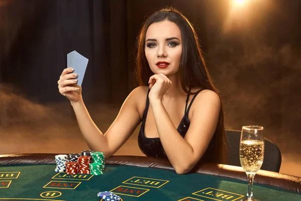 Hinreißende junge Frau sitzt am Pokertisch mit einem Glas Champagner — Stockfoto