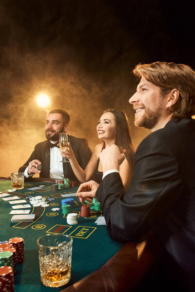Group of young rich people is playing poker in the casino