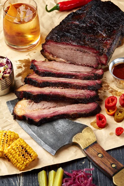 Fresh Brisket BBQ beef sliced for serving against a kraft paper background with sauce, hot peppers and corn. — Stock Photo, Image
