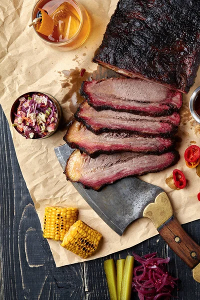 Fresh Brisket BBQ beef sliced for serving against a kraft paper background with sauce, hot peppers and corn. — Stock Photo, Image