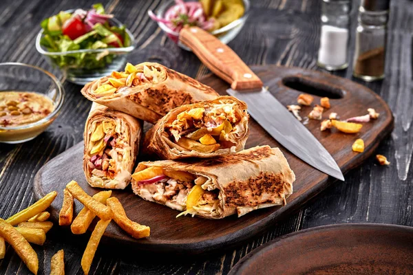 Rolo de frango Shawarma em uma pita com legumes frescos, molho de creme e batatas fritas em fundo de madeira. Foco seletivo — Fotografia de Stock