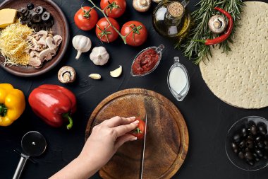 El ahşap tahta mutfak masa etrafında yalan malzemeler için pizza üzerinde domates kes: sebze, peynir ve baharatlar.