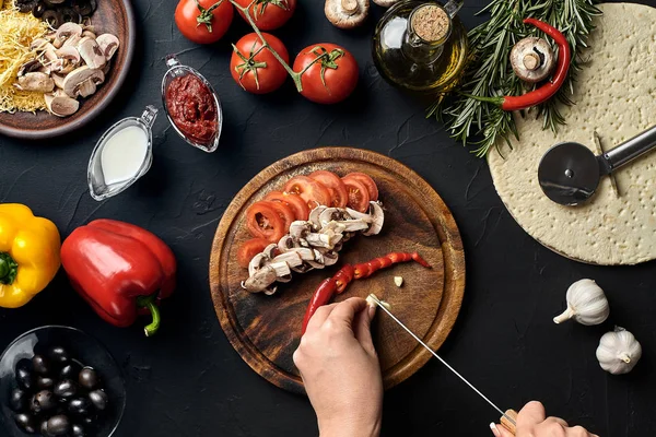 Ajo cortado a mano hembra, chile, champiñones y tomates en tablero de madera en la mesa de la cocina, alrededor de la mentira ingredientes para pizza: verduras, queso y especias . — Foto de Stock
