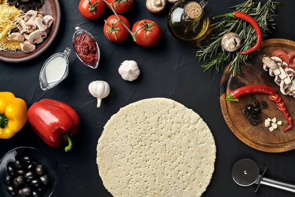 Ingredientes de pizza cruda sobre fondo de tabla de textura negra — Foto de Stock