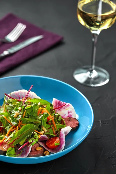 Fatias de carne picante salada de carne com tomate, salsa, rabanete e salada folhas espinafre na tabela de fundo textura preta — Fotografia de Stock