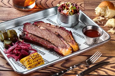 Smoked barbecue beef brisket with sauce, corn, marinated cucumber and onions clipart