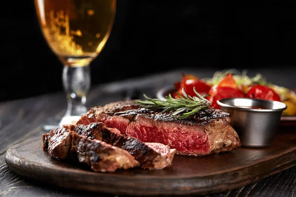 Bife suculento carne rara média com especiarias em tábua de madeira na mesa — Fotografia de Stock