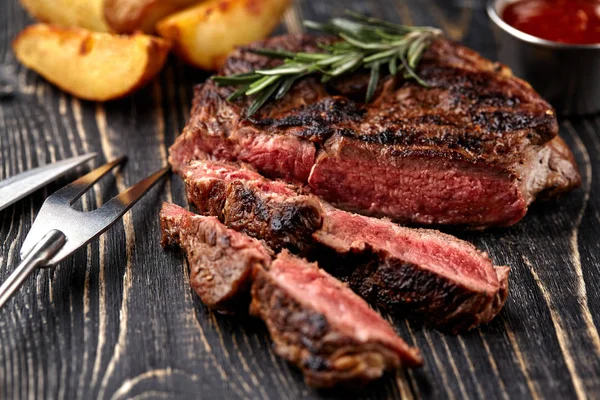 Carne de res jugosa mediana rara con especias en tablero de madera en la mesa — Foto de Stock