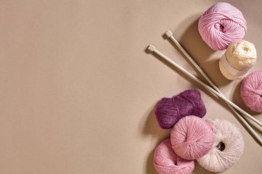 İplik ve örme iğneler bej renkli arka plan üzerinde renkli topları bir grup