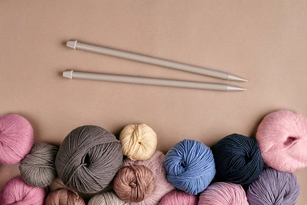 A group of colored balls of yarn and knitting needles on a beige background — Stock Photo, Image