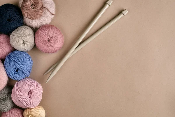 A group of colored balls of yarn and knitting needles on a beige background — Stock Photo, Image