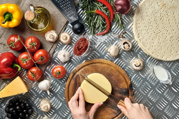 Vista parcial de la mujer cortando queso mientras cocina pizza italiana casera — Foto de Stock